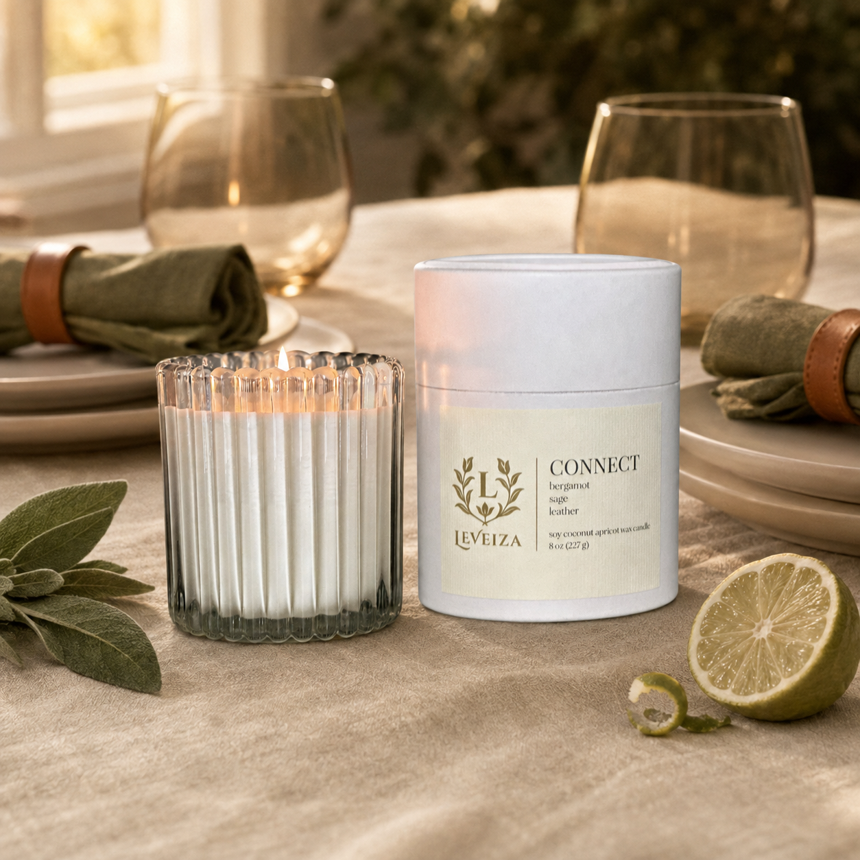 Lit Connect candle and tube on a warmly set dining table with sage, bergamot and olive linen napkins.
