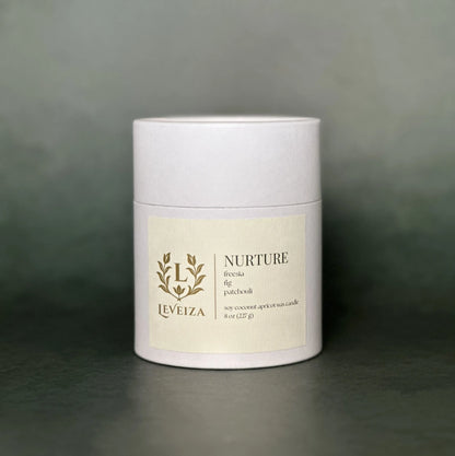 Leveiza Nurture candle white tube packaging with freesia fig patchouli scent notes