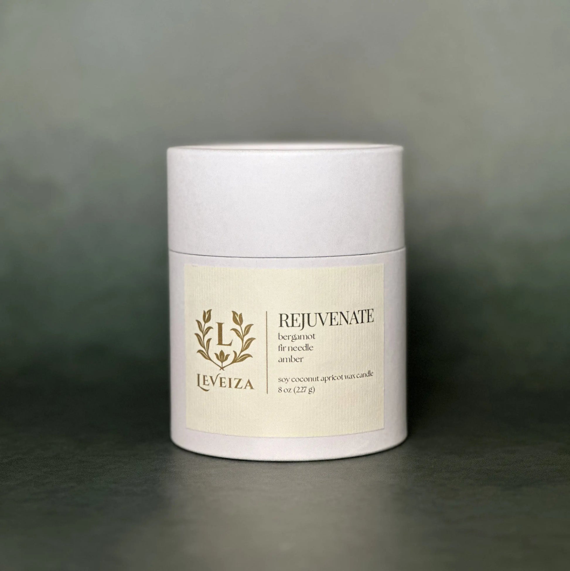 Leveiza Rejuvenate candle white tube packaging with bergamot fir needle amber scent notes