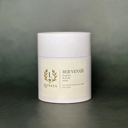 Leveiza Rejuvenate candle white tube packaging with bergamot fir needle amber scent notes