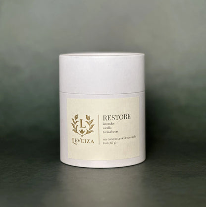 Leveiza Restore candle white tube packaging with lavender vanilla tonka bean scent notes
