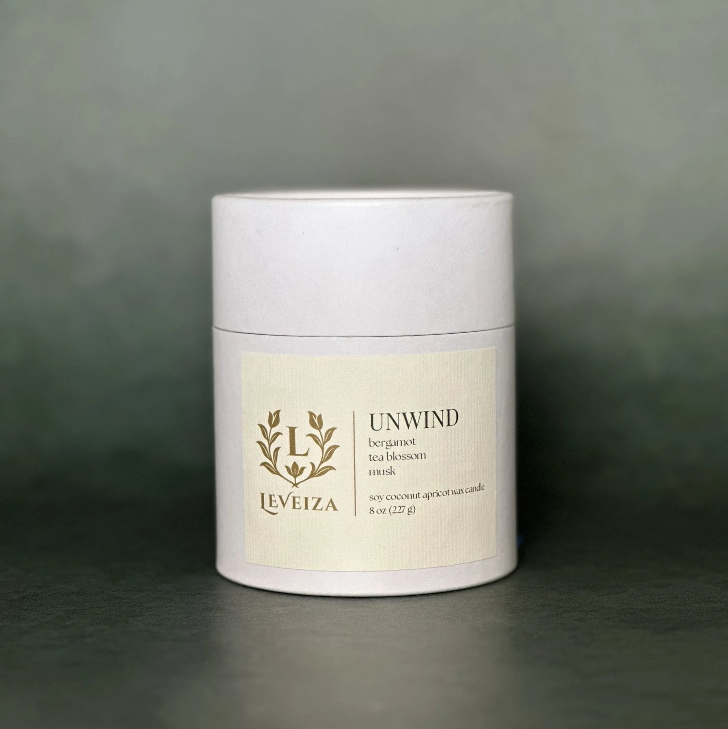Leveiza Unwind candle white tube packaging with bergamot tea blossom musk scent notes