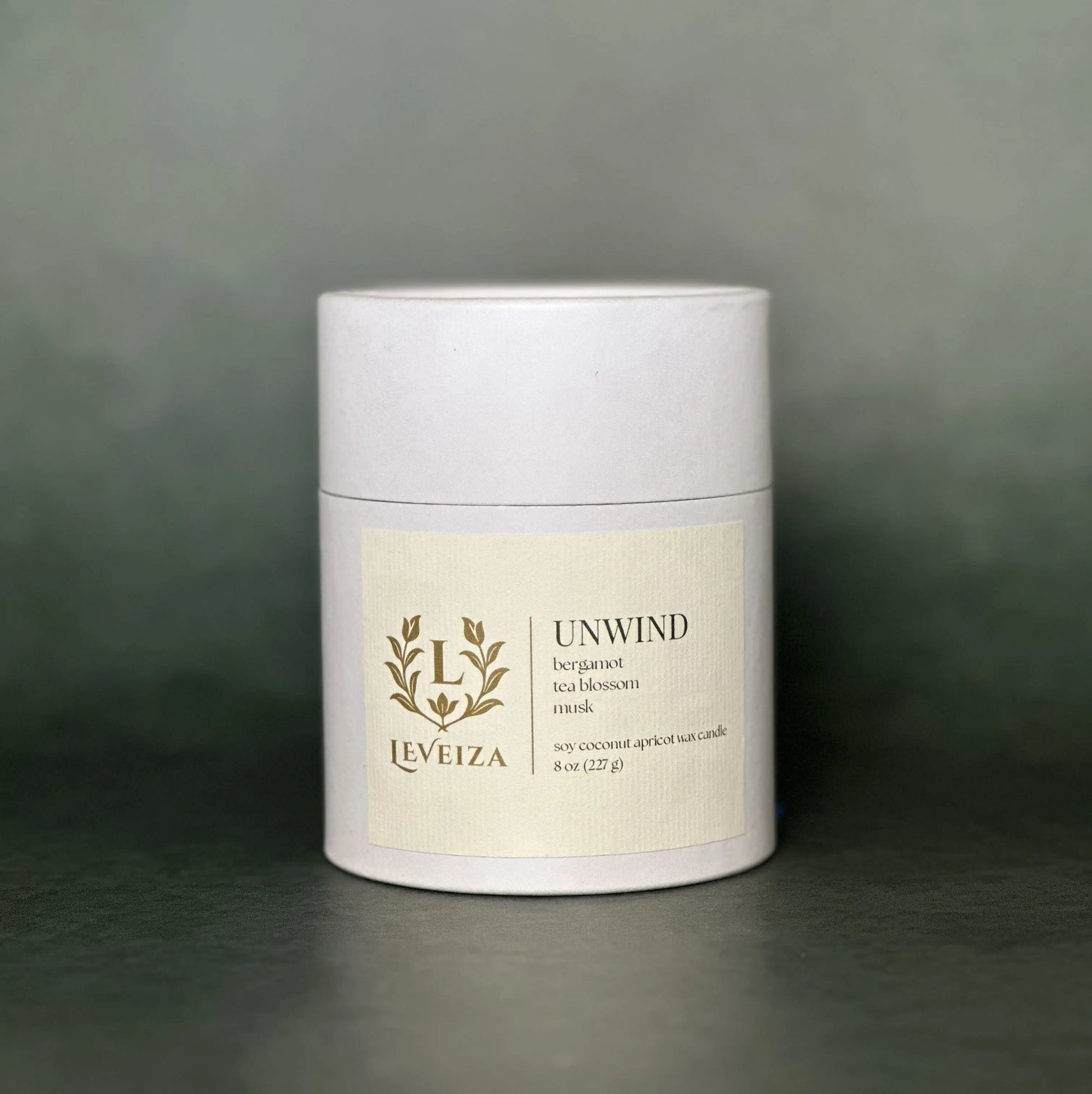 Leveiza Unwind candle white tube packaging with bergamot tea blossom musk scent notes