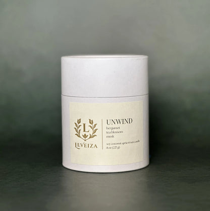 Leveiza Unwind candle white tube packaging with bergamot tea blossom musk scent notes