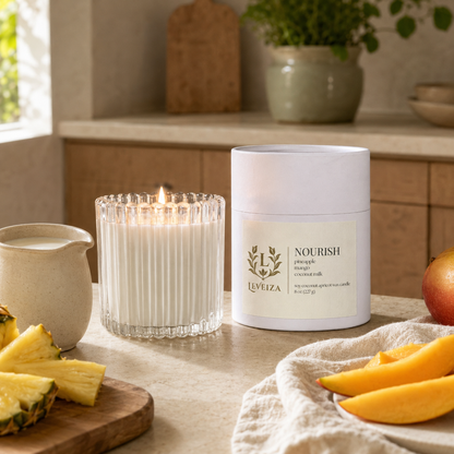 Lit Nourish candle and tube with pineapple, mango and coconut milk in a bright, welcoming kitchen.
